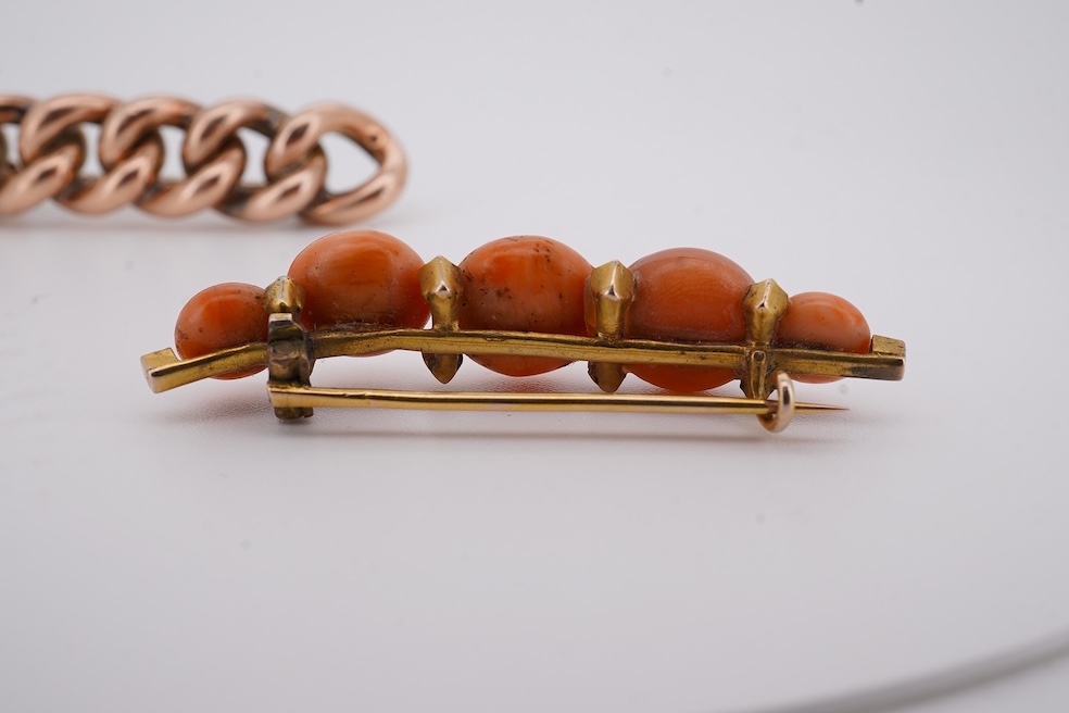 An early 20th century yellow metal and graduated five stone coral bead brooch, with seed pearl spacers, 45mm, together with a yellow metal curb link brooch and a yellow metal (stamped 9c) safety pin. Condition - fair